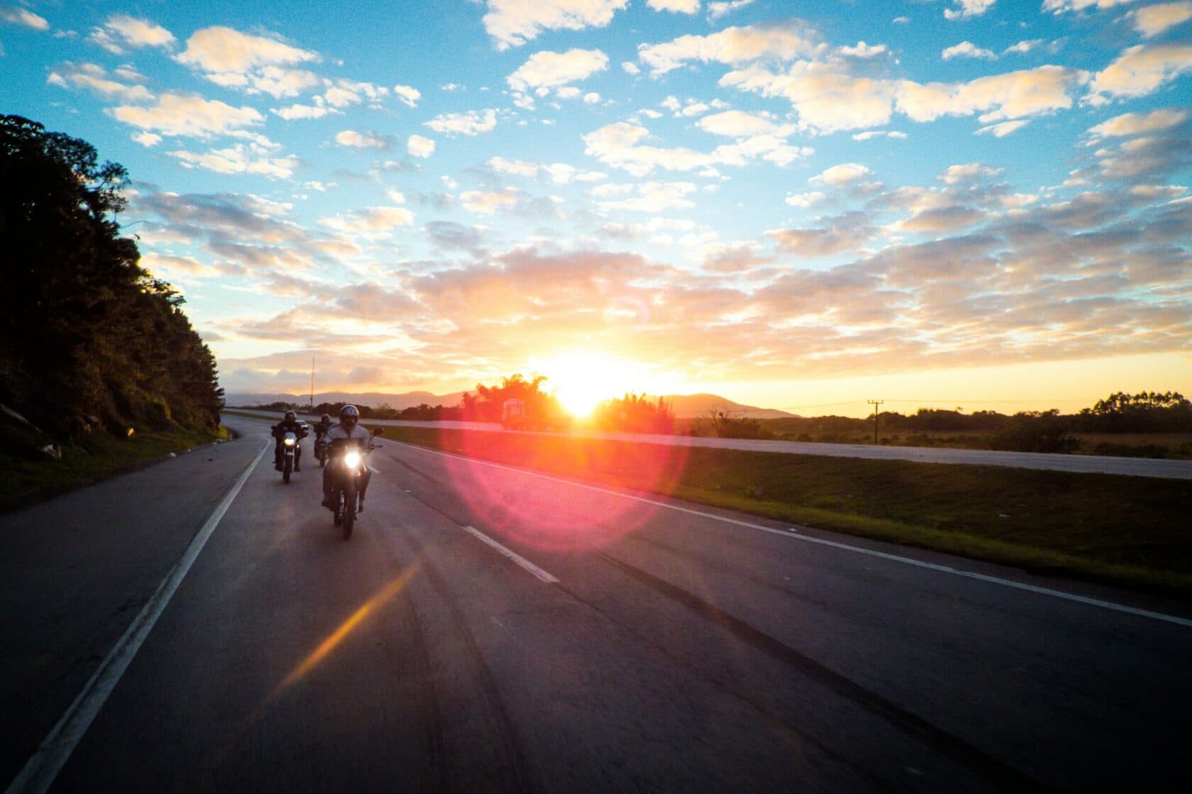 Motorcycle riders on the road at sunset